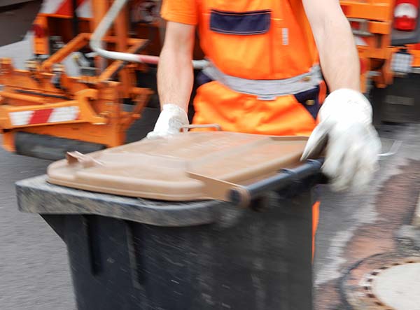 Foto: Ein Müllwerker hantiert mit einer Biotonne